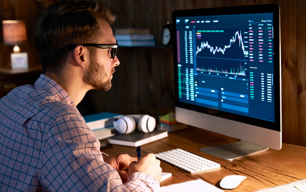 A man looking at graphs and data on a computer screen.