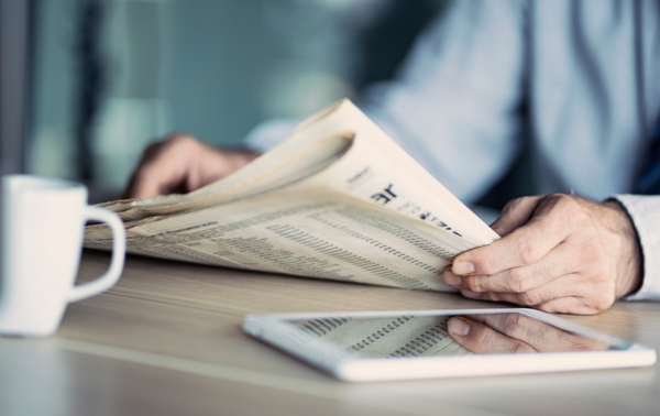 A man reading a newspaper at a table.