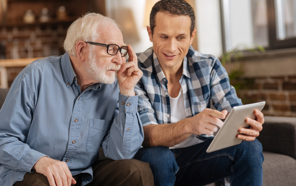 Young man showing his elderly father something on a tablet