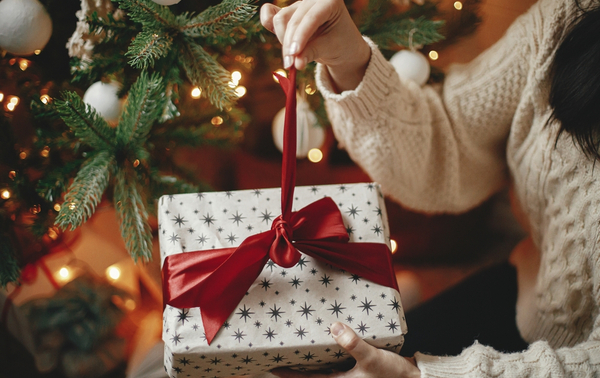 A woman unwrapping a Christmas gift.