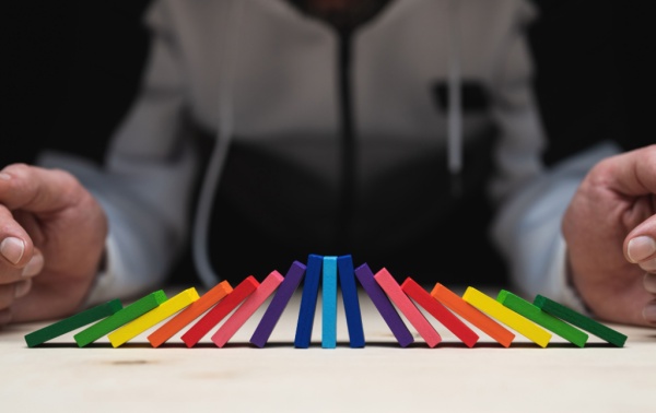 A line of coloured dominoes balancing on each other.