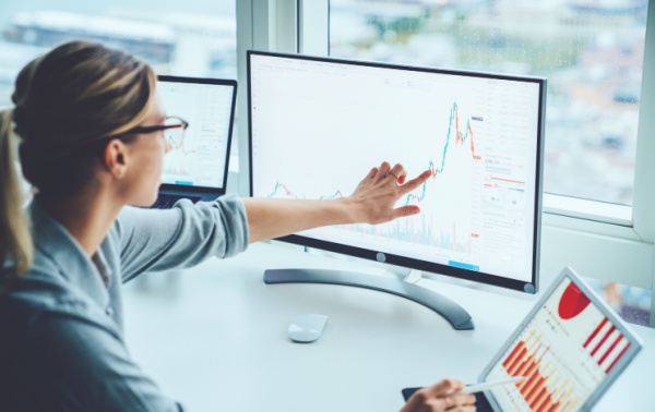 A woman looking at market performance on a computer screen