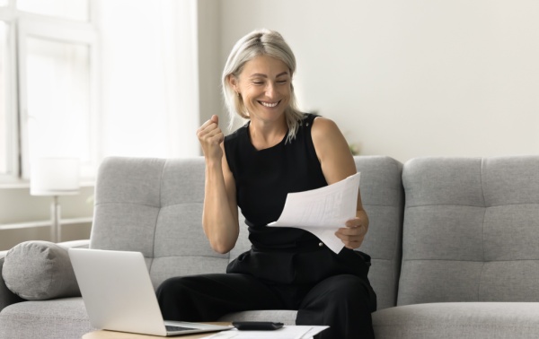 A woman smiling and looking at a document.