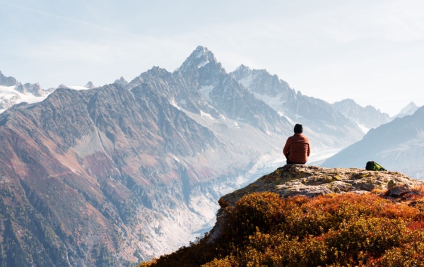 A man sitting on a hill and looking at a mountaintop
