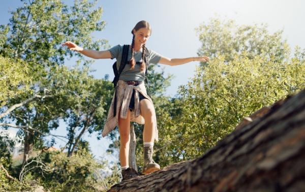 A woman balancing as she walks over a tree